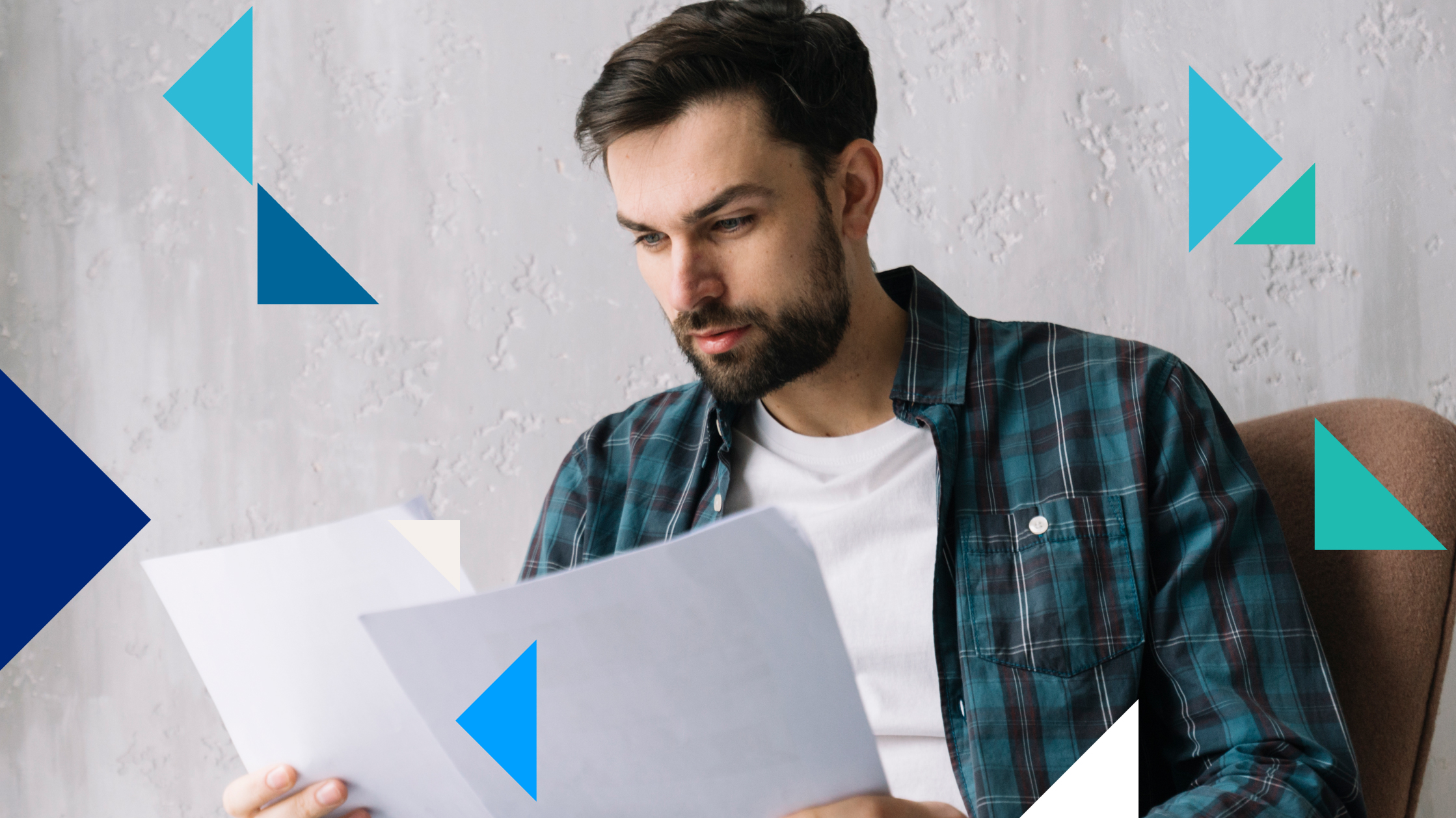 Un homme vêtu d'une chemise rayée bleu-vert regarde deux feuilles de papier avec concentration.