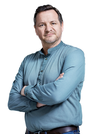 A man wearing a blue shirt smiles with crossed arms.