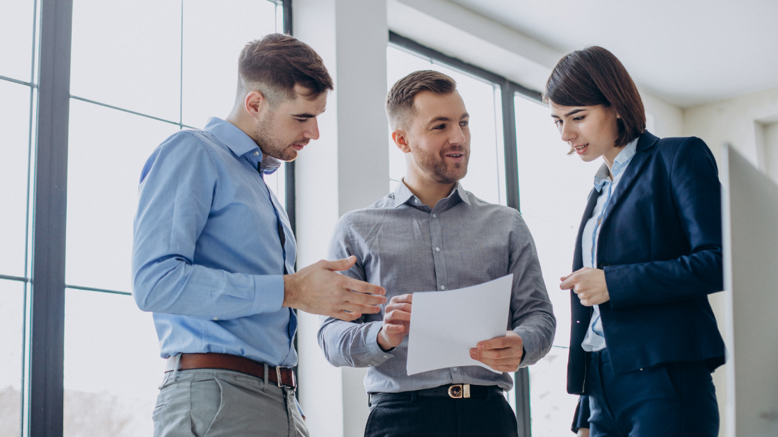 Two men and a woman look at a piece of paper.