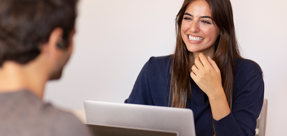 A woman smiles widely as she looks at a man.